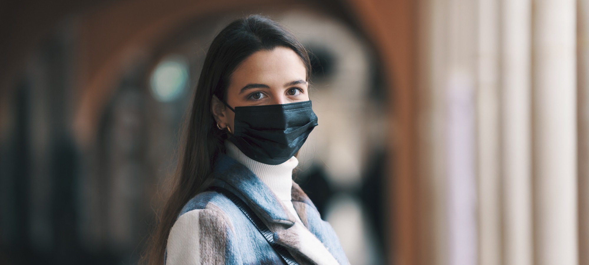 Young woman with mask looks at camera
