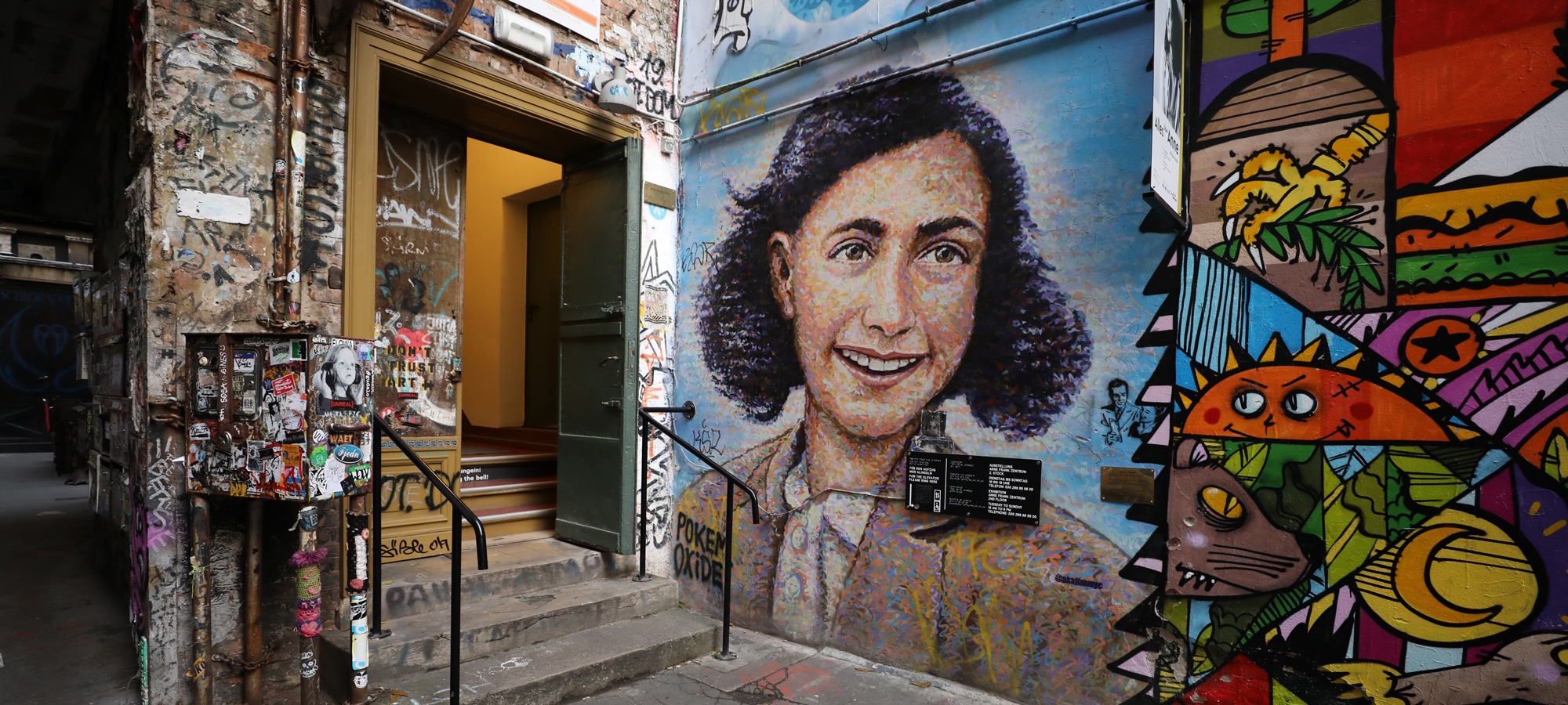 Hauseingang neben einer Mauer mit einem Bild von Anne Frank
